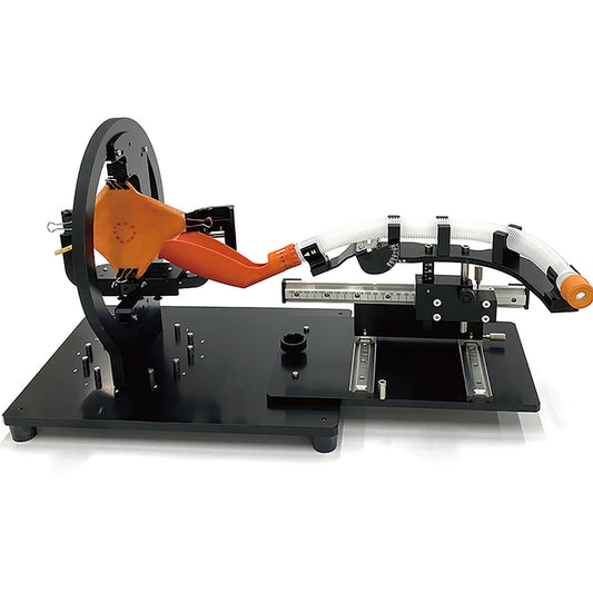 KOTOBUKI Medical's endoscopic submucosal dissection (ESD) training system. The unit is black and open-air, with a rotatable setting wheel that holds plant-based gastric mucosa tissue models. A spatula and tube sit at the other side for endoscopic entry.