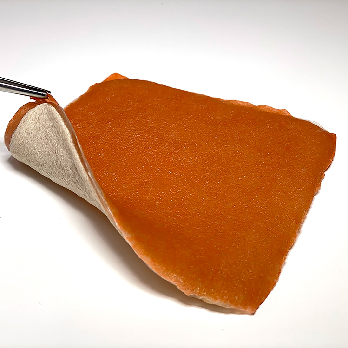 Medical forceps lift one corner of the VTT Mucosa Model. The base layer is white and dense, representing the muscularis. It is separate from the top mucosal layer by a thin, soft submucosal layer. All layers are made of the same plant-based tissue.