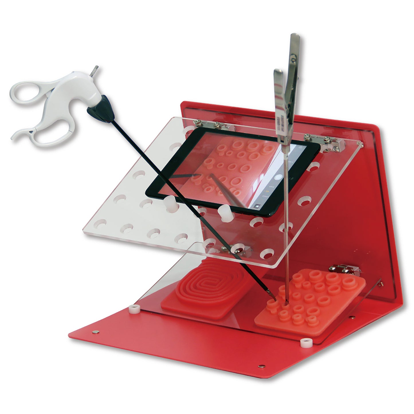 The Laparo Training Binder opened to its standing position. The red A4 binder is open and the clear laparoscopic wall has an iPad resting on top with its camera on. Two laparoscopic trocars are inserted into entry ports. A red silicon traning pad and a pink silicon training pad are being used to practice ligatures.