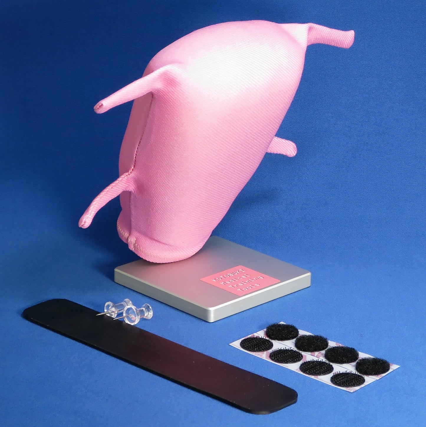A pink Laparoscopic Myectomy model is propped up on its base for training. This model has four tube-like fabric structures, two on each side, to represent serosa.