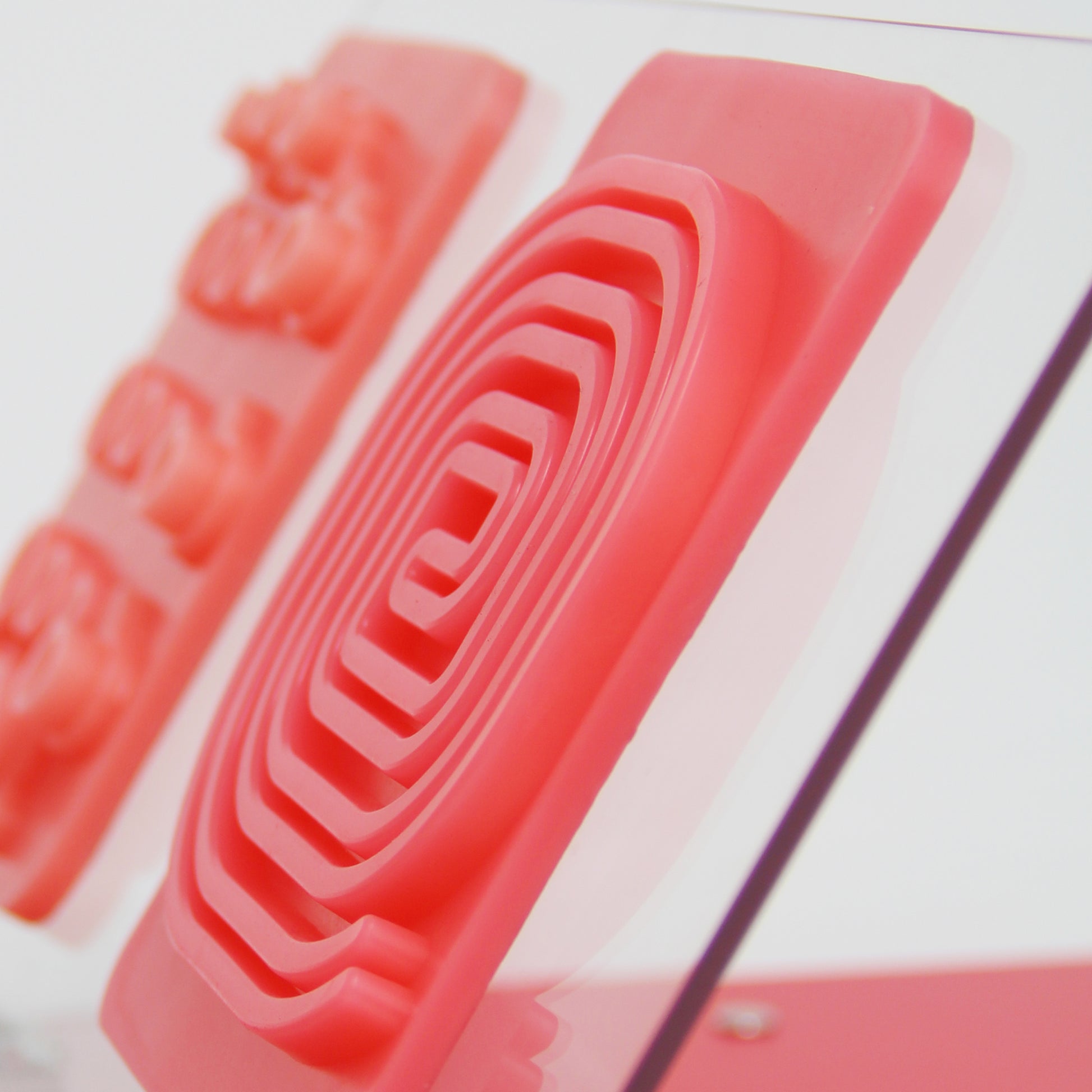 Closeup of the Training Pad Swirl from the side. It's propped up on a clear training platform. Another ligature pad can be seen in the background.